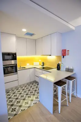 a kitchen with white cabinets and a table in it at Porto Views & Wines by Porto City Hosts in Vila Nova de Gaia