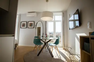 a dining room with a table and two green chairs at Porto Views & Wines by Porto City Hosts in Vila Nova de Gaia