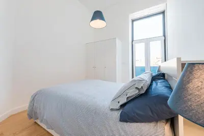 a bedroom with a bed with blue pillows and a window at GuestReady - Modern stay in downtown Porto in Porto