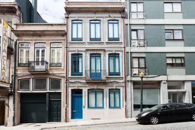 a car parked in front of a building with blue doors at Home Alegria in Porto
