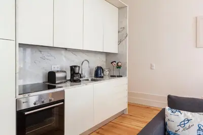 a kitchen with white cabinets and a stove top oven at Home Alegria in Porto