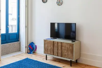 a flat screen tv sitting on top of a wooden cabinet at Home Alegria in Porto