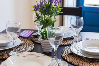 a table with plates and glasses and a vase with purple flowers at Home Alegria in Porto