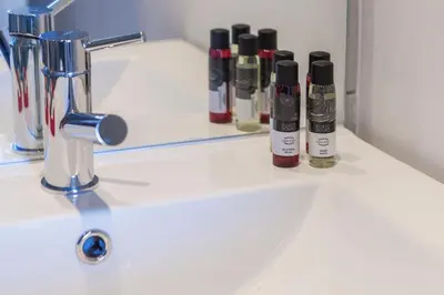a bathroom sink with four bottles of lipstick on it at Sunny Home in Porto