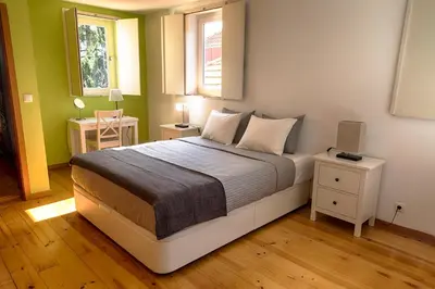 a bedroom with a bed with two tables and a window at Casa da Oliveira in Porto