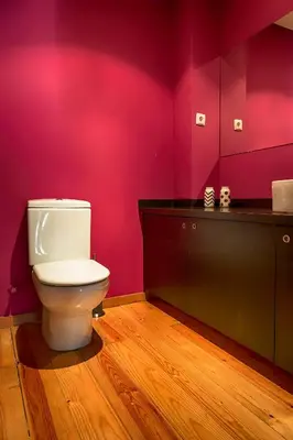 a bathroom with a toilet and a pink wall at Casa da Oliveira in Porto