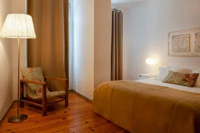 a bedroom with a bed and a lamp and a chair at OportoHouse in Porto