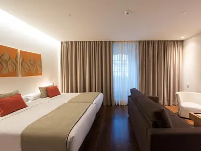 a bedroom with two beds and a window with a sink at Hotel Carris Porto Ribeira in Porto