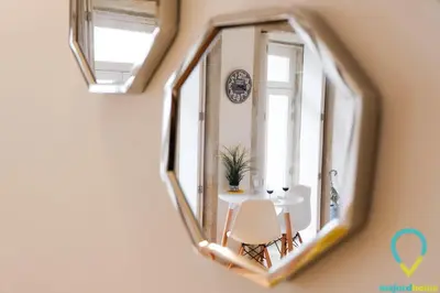 a mirror reflecting a room with a table and a clock at Lovely Porto in Porto