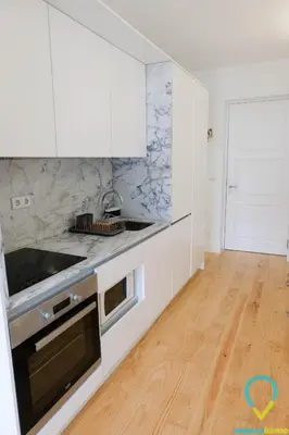 a kitchen with white cabinets and a wooden floor at Lovely Porto in Porto