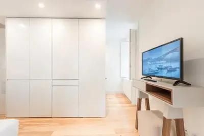 a living room with white cabinets and a flat screen tv at GuestReady - The New Yellow Ledbetter in Porto