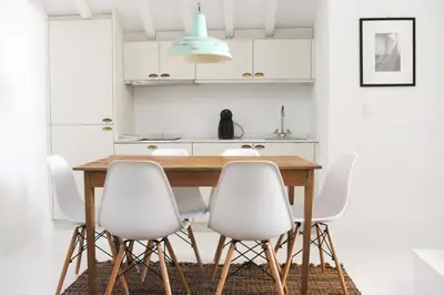 a kitchen with a wooden table and white chairs at Mo House in Porto