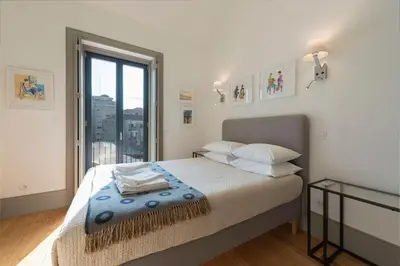 a bedroom with a bed and a large window at Bom-Jardim Trindade in Porto