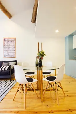 a dining room with a glass table and white chairs at Oliveirinhas Porto Apartment in Porto