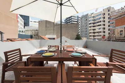 a wooden table with chairs and an umbrella on a balcony at BmyGuest - 156 Trindade House & Terrace in Porto