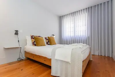 a bedroom with a bed with white sheets and a rug at Liiiving in Porto - Santa Catarina Luxury Apartment in Porto
