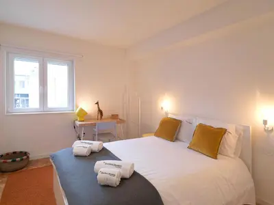 a bedroom with a large white bed with towels on it at FLH Porto Central Apartment in Porto