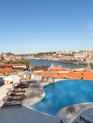 a large swimming pool with lounge chairs and umbrellas at The Yeatman in Vila Nova de Gaia