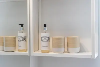 a white cabinet with four bottles and cups at Casa do Ofício - Caldeireiro in Porto