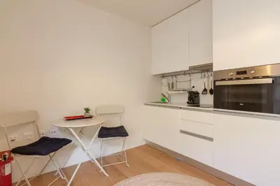 a kitchen with white cabinets and a small table in it at Secret Camões in Porto