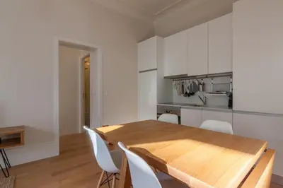 a kitchen with a wooden table and white cabinets at Terrace Camões in Porto