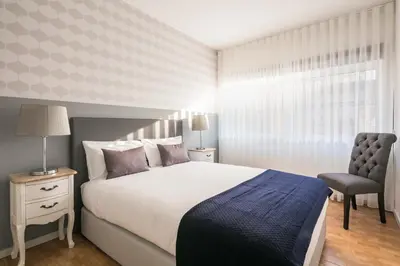 a bedroom with a bed and a chair and a window at Camarinha Oporto Apartments in Porto