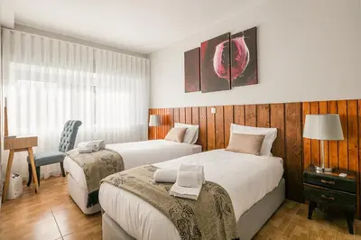 a hotel room with two beds and a chair at Camarinha Oporto Apartments in Porto