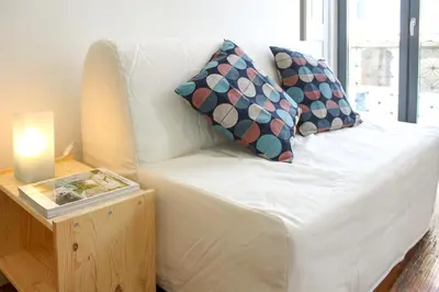 a white couch with pillows and a table with a candle at Bonjardim Flats - T1 com varanda in Porto