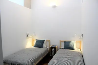 two twin beds in a room with white walls at Bonjardim Flats - T1 com varanda in Porto