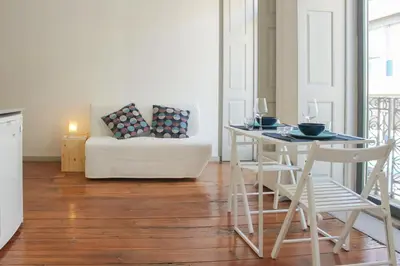 a living room with a table and a white couch at Bonjardim Flats - T1 com varanda in Porto