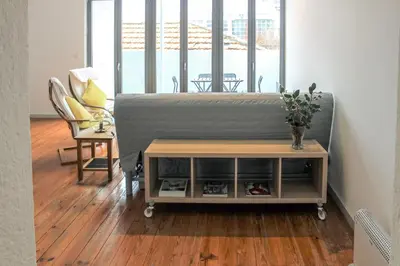 a living room with a bed and a table and a chair at Bonjardim Flats - T2 com Varanda in Porto