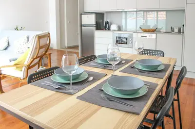 a wooden table with plates and wine glasses on it at Bonjardim Flats - T2 com Varanda in Porto
