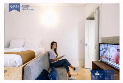 a woman sitting on a couch in a hotel room at ORM - 3 C´s Apartments in Porto