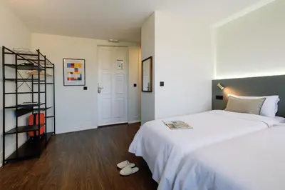 a bedroom with a large white bed and wooden floors at Cosme Apartments by Olala Homes in Porto