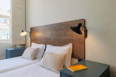 a bedroom with a bed with a wooden headboard and a table at Cosme Apartments by Olala Homes in Porto