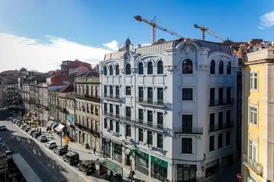 a large white building on a city street with cars at Mouzinho Cosy LOFT in Porto