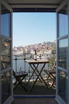 a table and chairs on a balcony with a view of the water at Porto View by Patio 25 in Vila Nova de Gaia