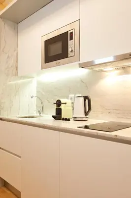 a white kitchen with a sink and a microwave at LOFT Sá de Noronha in Porto