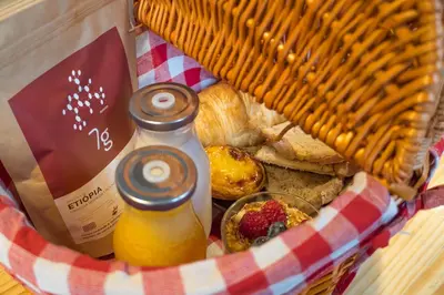 a basket of food with bread and a bottle of juice at 7 Gaia Roaster Apartments in Vila Nova de Gaia