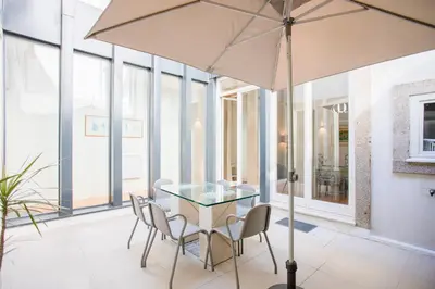 a table with chairs and an umbrella in a room with windows at Liiiving in Porto | Central Secret Terrace in Porto