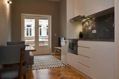 a kitchen with a counter and a table and a door at De Porto e Alma in Porto