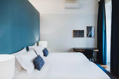 a bedroom with a white bed with blue accents at VIVA 4 Suites Batalha Residence & SIZE Flats Batalha in Porto