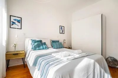 a white bedroom with a large bed with blue pillows at LAZ apartment in Porto