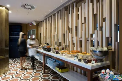 a woman standing in front of a buffet line with food at Pestana Porto - A Brasileira, City Center & Heritage Building in Porto