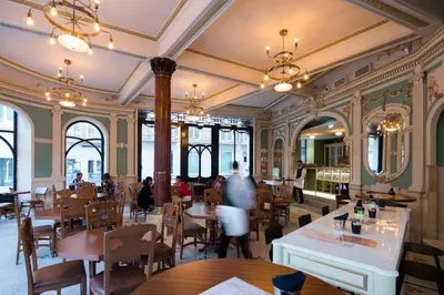 a restaurant with tables and chairs and people in it at Pestana Porto - A Brasileira, City Center & Heritage Building in Porto