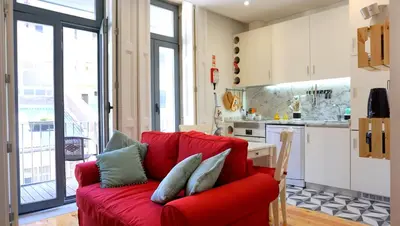 a red couch in a living room with a kitchen at Casa da Andorinha, charm apt Porto Bolhão in Porto