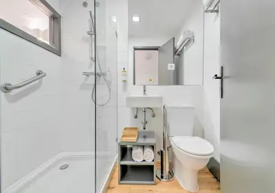 a white bathroom with a toilet and a shower at Oporto Street Fonte Taurina - Riverfront Suites in Porto