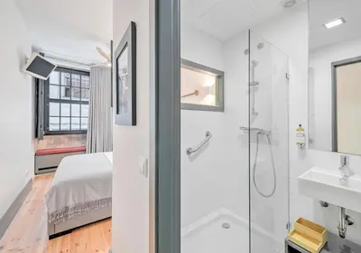 a bathroom with a shower and a sink and a bed at Oporto Street Fonte Taurina - Riverfront Suites in Porto