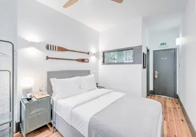 a white bedroom with a bed and a window at Oporto Street Fonte Taurina - Riverfront Suites in Porto