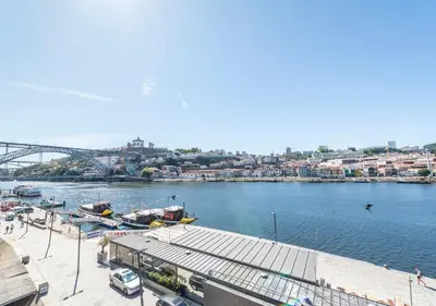 a view of a river with boats and a bridge at Oporto Street Fonte Taurina - Riverfront Suites in Porto